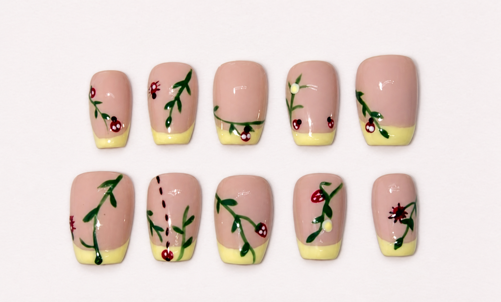 Soft pink nails with pale yellow French tips and delicate flower stems