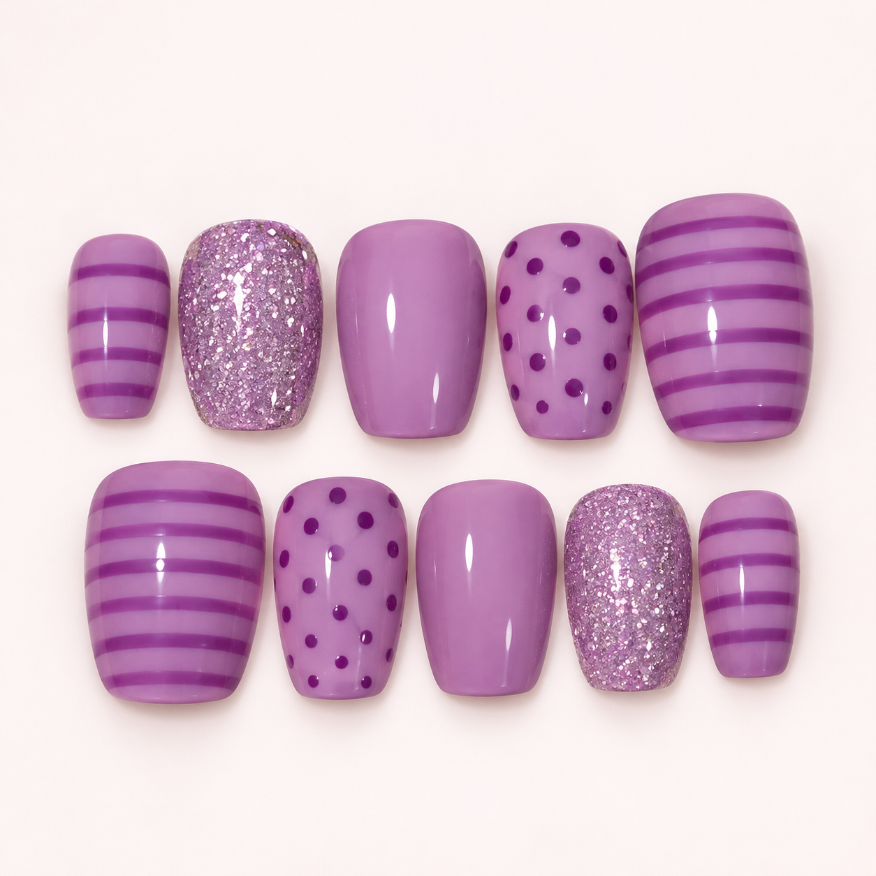 Purple nails with glitter, polka dots, and stripes