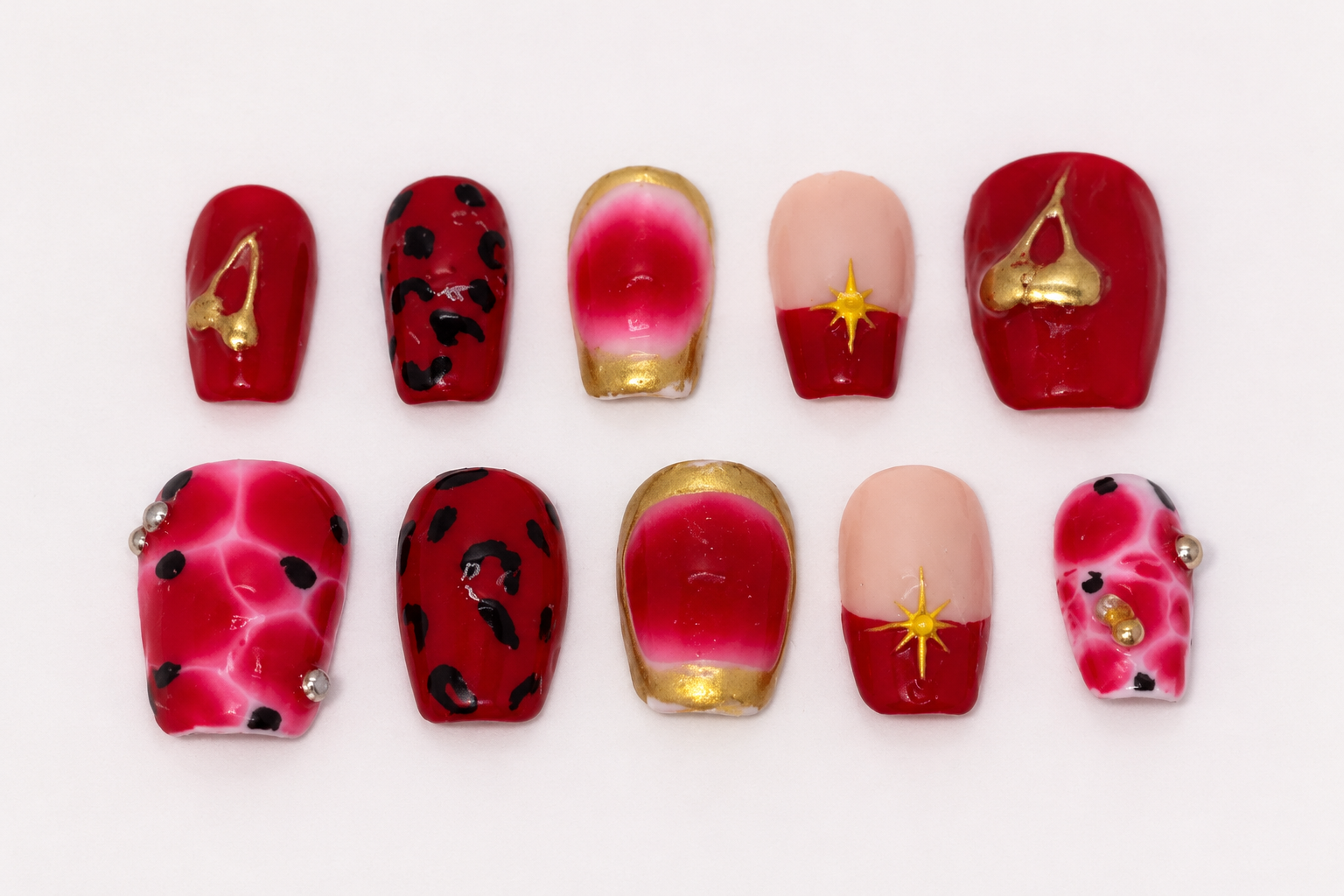 Red and gold nails with leopard print, French tips, and jeweled accents